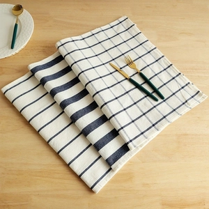 Close-up of blue striped and checkered waffle tea towels with gold cutlery on wood