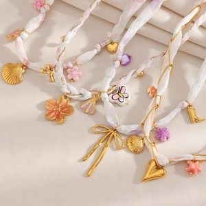 Vue détaillée du collier ruban plaqué or 18K avec breloques cœur et fleurs en émail