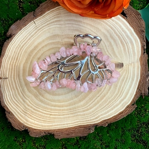 Detailed macro of crystal butterfly hair claw with pink stones on a natural wood surface
