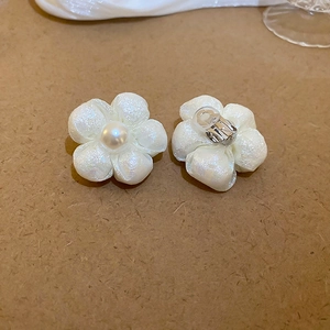 Detailed view of sweet fabric flower earrings with faux pearl center and pearly finish