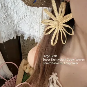Detailed view of large handmade straw flower clip-on earrings worn by a model