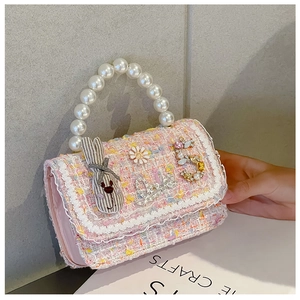 Detail of pink tweed girl's handbag with pearl handle, lace trim, and cute charms