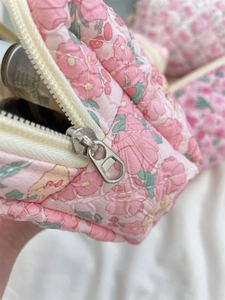Detailaufnahme des rosa geblümten Steppstoffs und des Metallreißverschlusses der Tasche