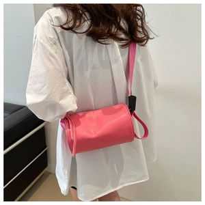 Dettaglio della borsa cilindrica rosa con tracolla larga indossata da una modella