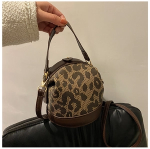 Detailed view of leopard print bucket bag with brown leather handles and gold hardware