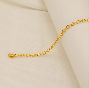 Detail of a gold stainless steel cable chain bracelet featuring a secure lobster clasp