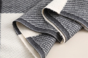 Detailed macro view of the soft grey and white checkered faux cashmere knit fabric