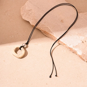 Close-up of beige stone-textured resin ring and silver bead on black leather cord