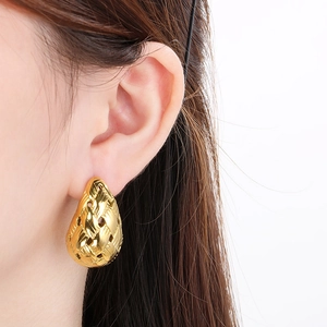 Close-up of golden woven teardrop earrings worn by model showing vintage texture