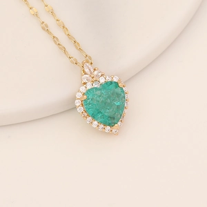 Golden stainless steel necklace with a green heart pendant on a display stand