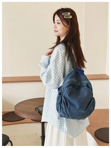 Casual blue denim backpack shown on a model in a cozy cafe setting for a vintage style