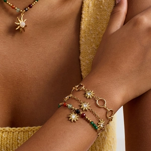 Detail of gold sun bracelets and necklace with rhinestones and colorful beads on model