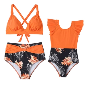 Détail de maillots de bain parents-enfants orange vif avec imprimé feuilles de palmier tropicales