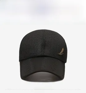 Close-up of black baseball cap with mesh texture and gold feather metal logo detail