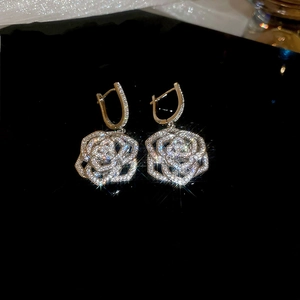 Detailed macro view of silver flower earrings with white zircon pavé on black background