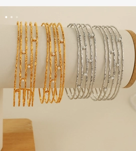 Detail of multi-layered C-shaped bracelets with hammered texture and white pearls