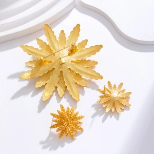 Elegant gold leaf wheat brooch and stud earrings set on a white textured background