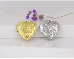 Detail of gold and silver heart locket pendants with intricate floral and vine engraving