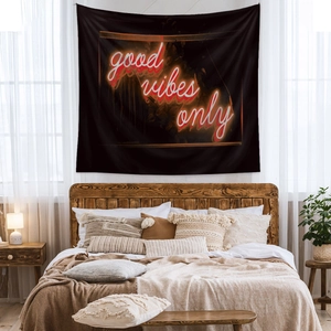 Detail of neon 'good vibes only' lettering on black tapestry hanging in a cozy bedroom
