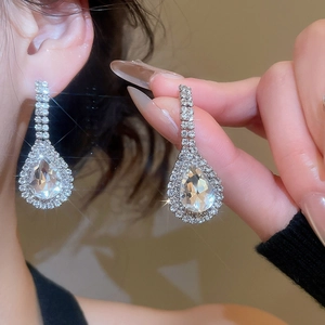 Detailed macro view of pear shaped silver drop earrings with shimmering pavé crystal setting