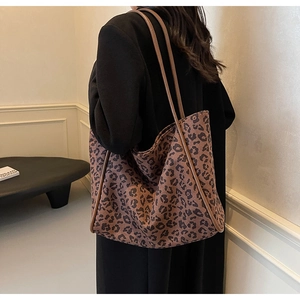 Detail view of large leopard print tote bag with brown straps on a model shoulder