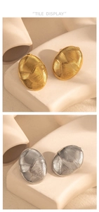 Macro detail of oval geometric earrings in gold and silver with linear texture finish