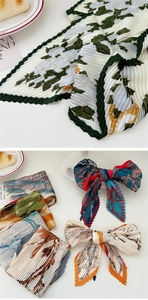 Macro view of pleated satin scarf with floral prints and fine accordion fold details