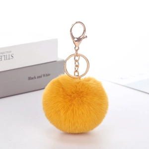 Close-up of bright yellow faux rabbit fur keychain with golden lobster clasp on white surface