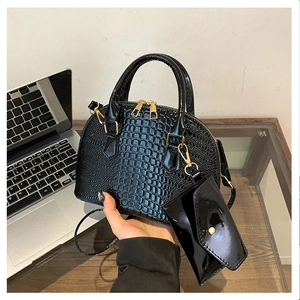 Detail view of black crocodile pattern shell bag with gold hardware and small pouch