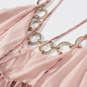 Dettaglio dell'abito in chiffon rosa con eleganti anelli metallici dorati sulle spalline