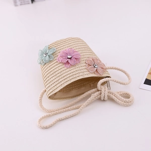 Detail of straw woven crossbody bag with mesh flower decorations and center rhinestones