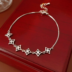 Détail du bracelet plaqué or 18k avec motifs étoiles et zircons sur support bois