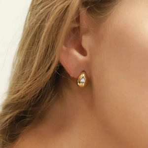 Close-up of golden teardrop stud earrings with clear gemstone on model for daily wear