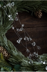 Close-up of clear acrylic icicles and crystal beads on a pine branch for Christmas