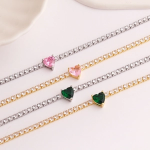 Macro view of gold and silver tennis bracelets with pink and green heart-shaped zircons