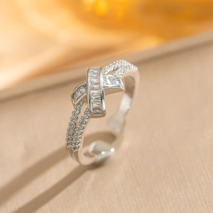 Detail eines kreuzförmigen Rings mit rechteckigen Zirkonia auf warmem Seidenstoff