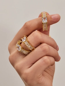 Close-up of gold-plated rings with baguette-cut cubic zirconia in a layered look