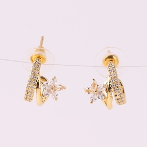 Macro view of gold flower earrings with spiral design and sparkling zircon crystals