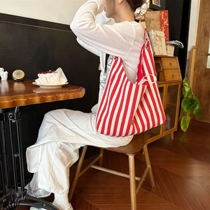 Détail d'un grand sac cabas en toile à rayures rouges et blanches porté par un mannequin