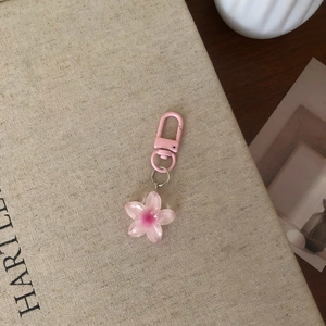 Pink resin flower keychain with matching metal clasp on a vintage book background