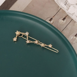 Detail of a gold starburst hair clip with sparkling rhinestones on a vintage plate