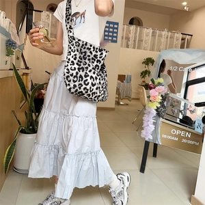 Detail of a large leopard print canvas tote bag styled in a bright minimalist cafe