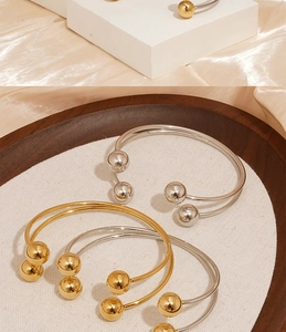 Detail of open ball bracelet in gold and silver finish on elegant satin and stone background