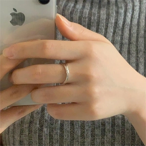 Detail of a minimalist silver bamboo-style open ring shown in a casual lifestyle mirror shot