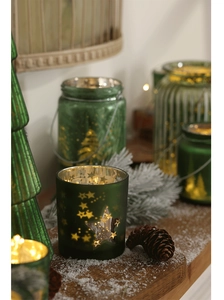 Close-up of green glass Christmas candle holders with star cutouts and warm LED lights