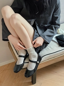 Close-up of black patent leather Mary Jane shoes paired with white ribbed cotton socks