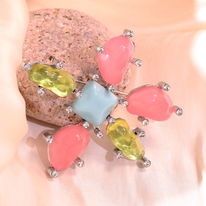 Detailed view of floral brooch with pink and yellow stones on elegant silk fabric