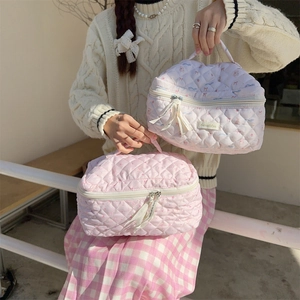 Close-up of pink quilted cosmetic bags with heart floral patterns and ribbon zippers