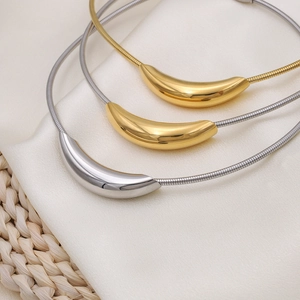 Minimalist gold and silver curved tube necklaces on elegant silk and woven background