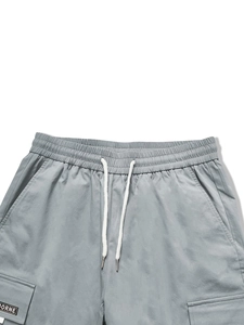 Detail der hellgrauen Cargohose mit elastischem Bund, weißem Kordelzug und aufgesetzter Tasche